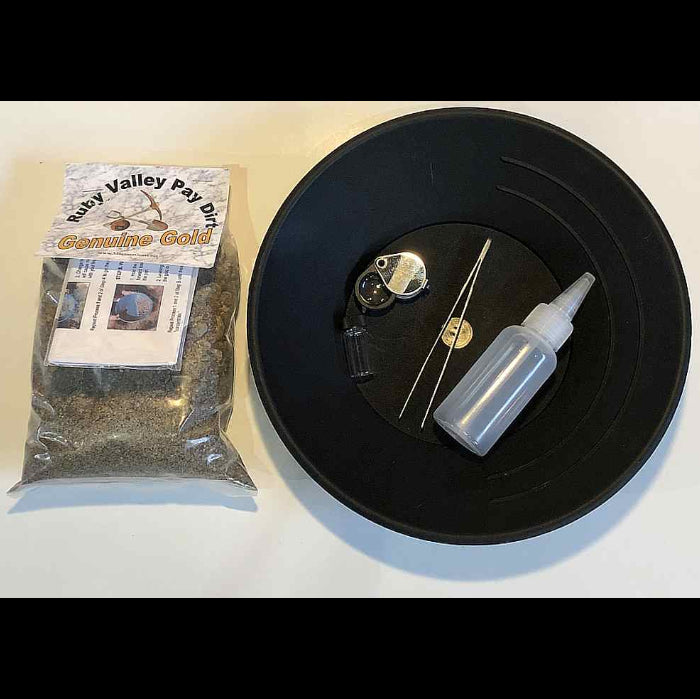 Black pan with gold panning tools and a bag of gold Pay Dirt.