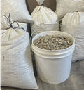 Bucket filled with gem mining material next to large gravel bags