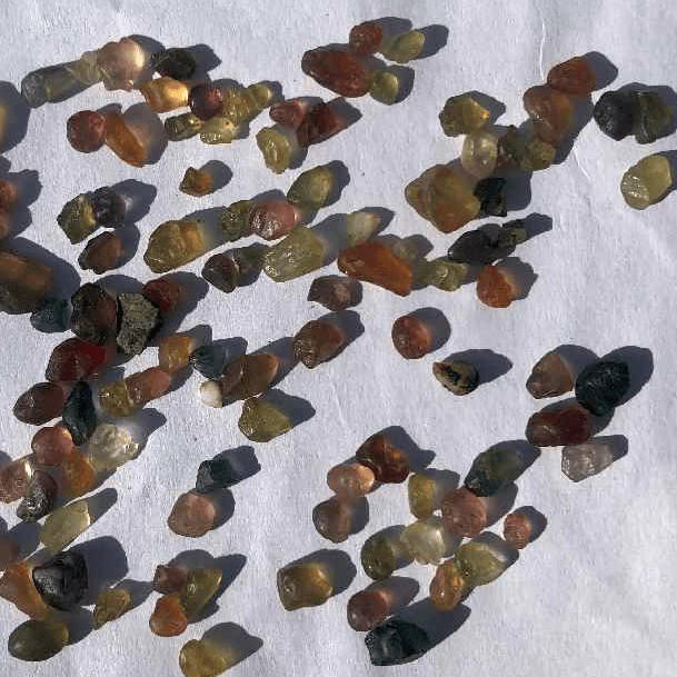 Small stones on a white background with a coin for scale